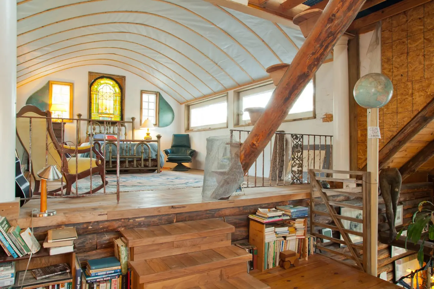 The loft with its brass bed, rocking chair and stained glass, seen from the stairs