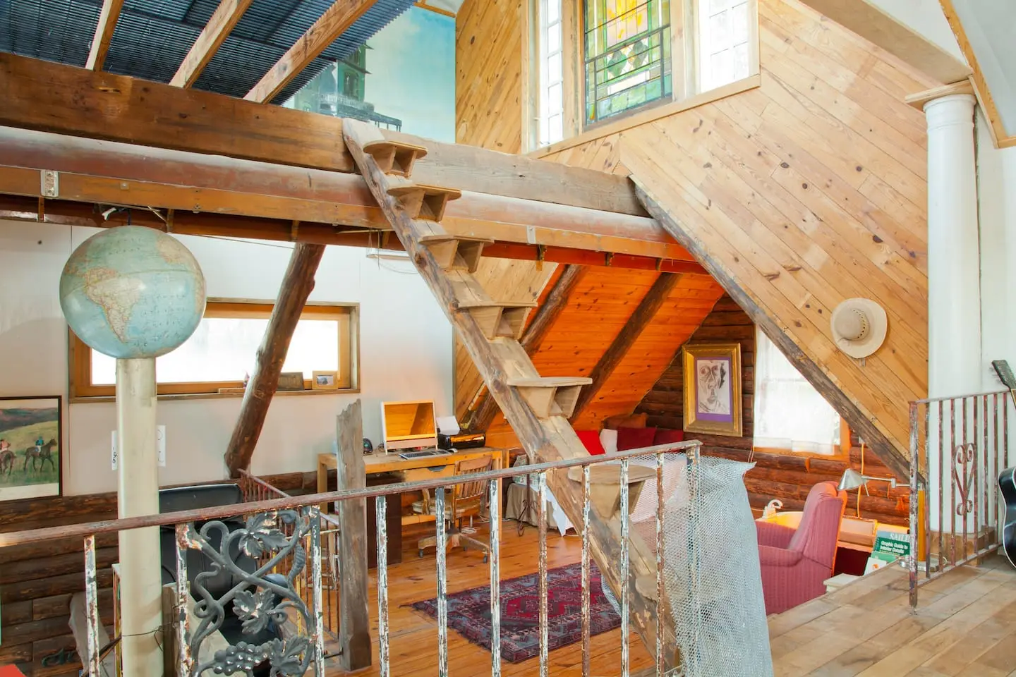 A floating timber staircase beside a globe lamp, a desk and a reading chair