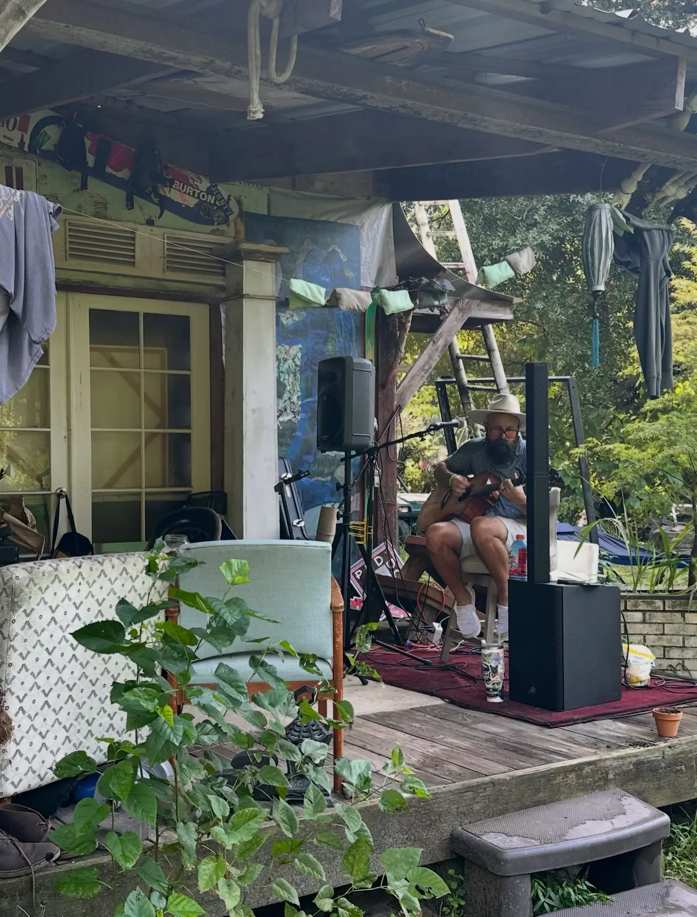 A singer-songwriter in a straw hat playing guitar on the porch stage